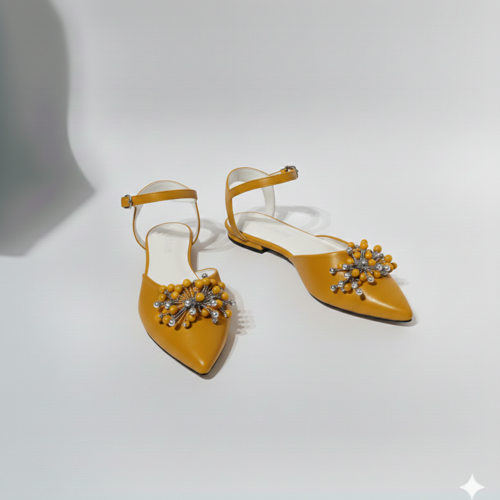 Pair of mustard yellow shoes with decorative embellishments on a light gray background