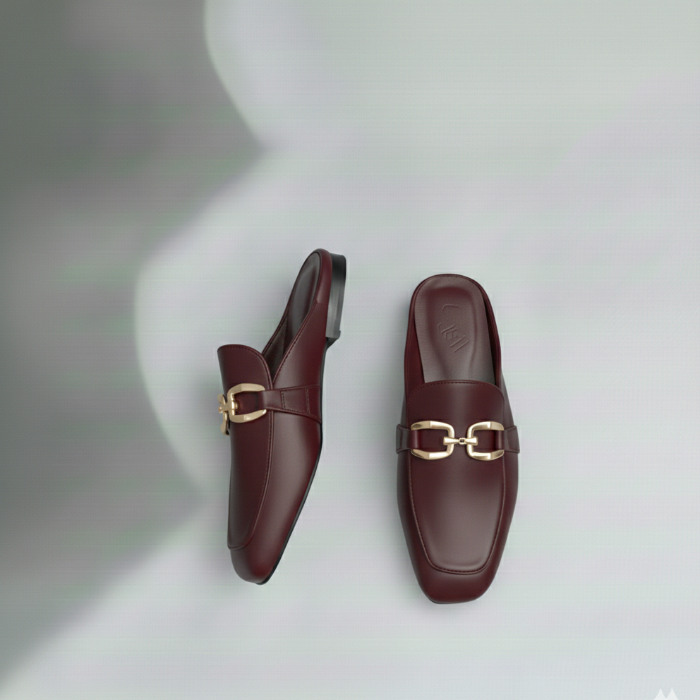 Pair of maroon loafers with gold buckles on a light gray background