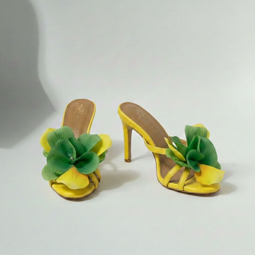 Yellow high-heeled shoes with green floral decorations on a white background