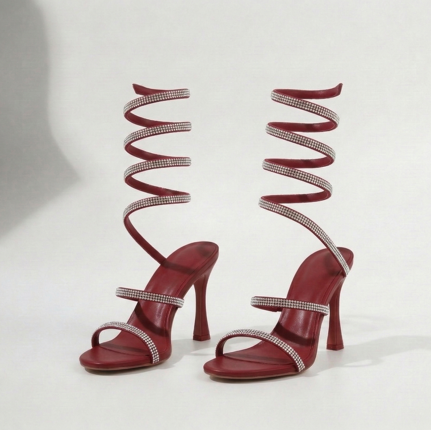 Red high-heeled shoes with spiral designs on a white background