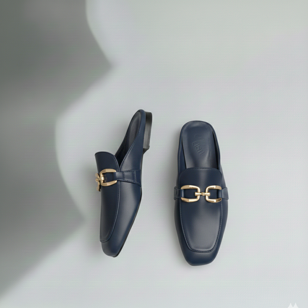 Pair of navy blue loafers with gold buckles on a light gray background
