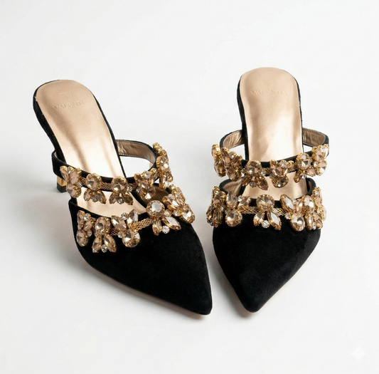 Black high-heeled shoes with gold embellishments on a white background