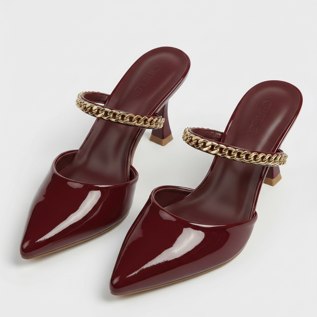 White pointed-toe shoes with gold chain details on a light gray background
