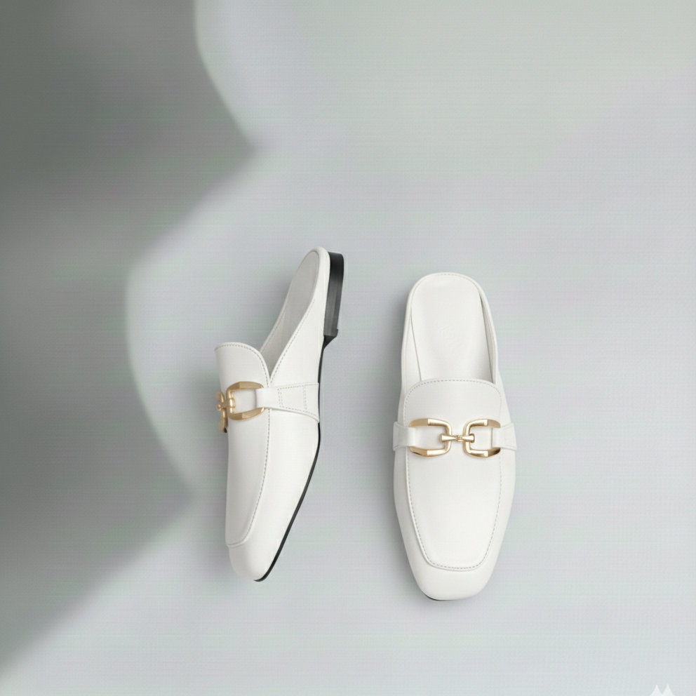 White loafers with gold buckles on a gray background