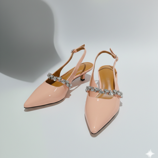 Pair of pink high-heeled shoes with embellished straps on a light gray background