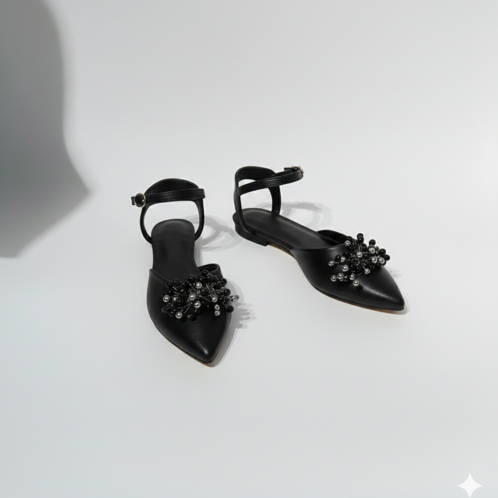 Black pointed-toe shoes with embellishments on a white background