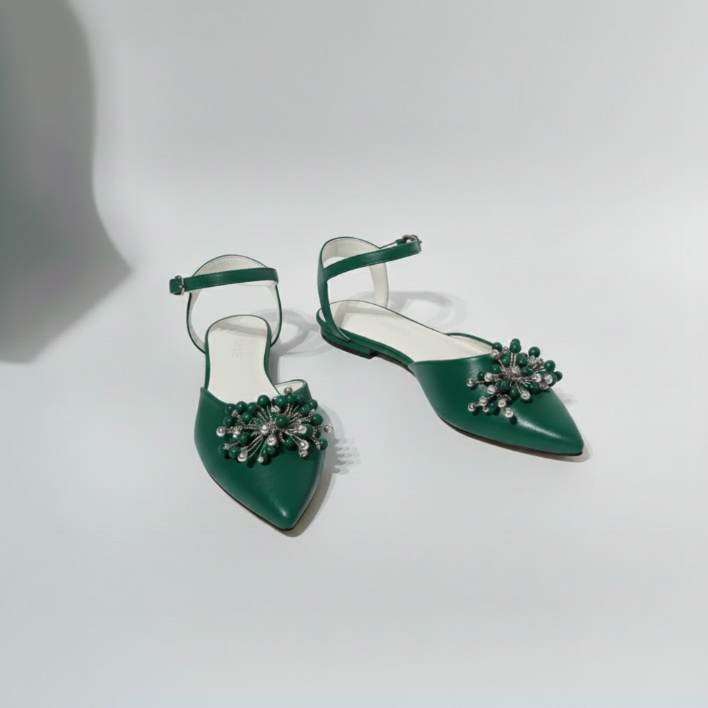 Green high-heeled shoes with embellishments on a light gray background