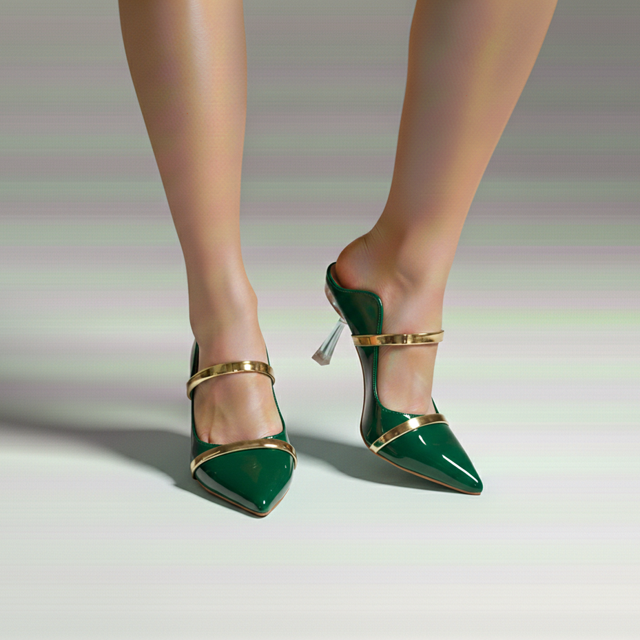 Green high-heeled shoes with gold straps worn by a person on a neutral background